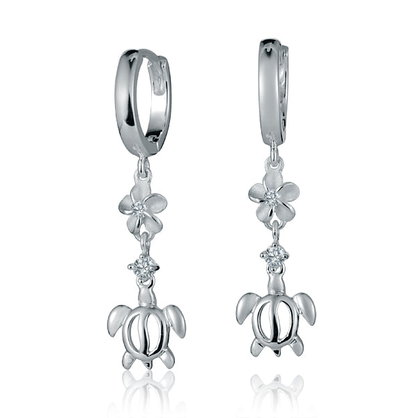 The picture shows a pair of sterling silver dangling hoop earrings featuring a plumeria and sea turtle motif with cubic zirconia.