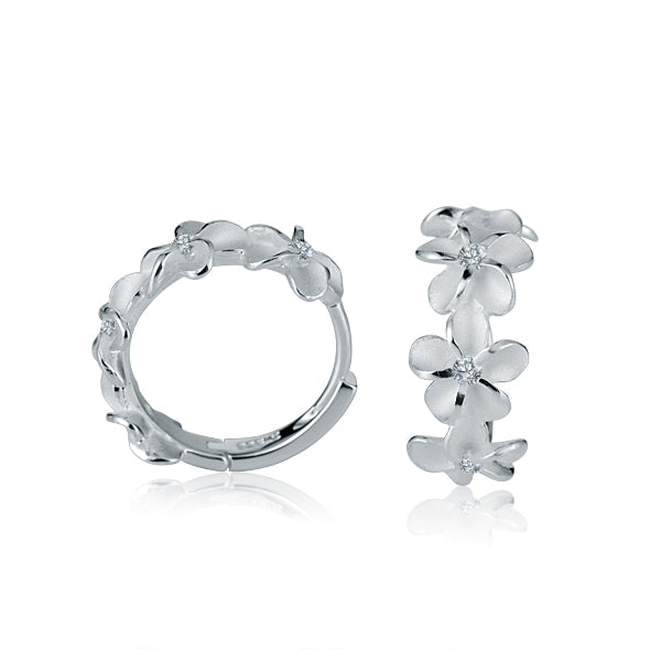 The picture shows a pair of matte finish sterling silver plumeria hoop earrings with white cubic zirconia.
