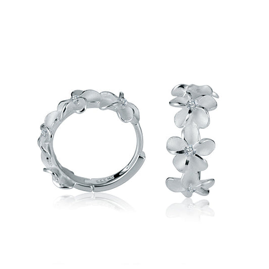 The picture shows a pair of matte finish sterling silver plumeria hoop earrings with white cubic zirconia.