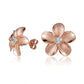 The photo shows a pair of rose gold vermeil plumeria stud earrings with cubic zirconia gemstones.