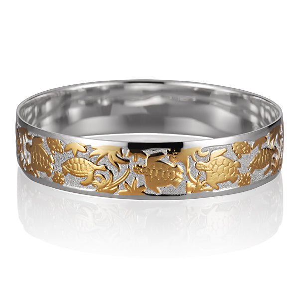 The photo is a two-tone white and yellow gold vermeil swimming turtle bangle. 