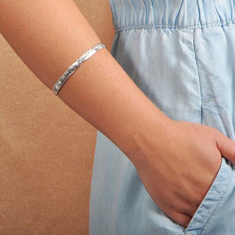 Model wearing a 6mm sterling silver bangle with the Hawaiian word "ku'uipo" engraved on it. 