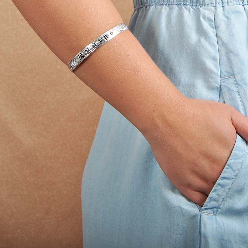 Model wearing an 8mm sterling silver bangle with the Hawaiian word "ku'uipo" engraved on it. 