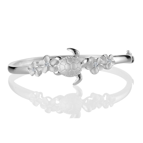 The picture shows a sterling silver four plumeria bangle featuring a sea turtle motif with cubic zirconia. 
