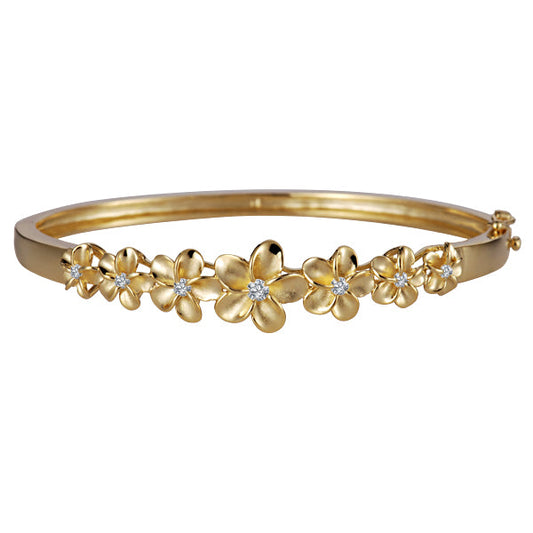The photo shows a yellow gold vermeil plumeria bangle with cubic zirconia. 