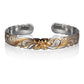 The photo shows a two-tone sterling silver yellow gold vermeil cuff bangle with a plumeria scroll motif. 