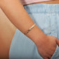 The photo shows the arm of a model wearing a rose gold vermeil flowering plumeria cuff bangle. 