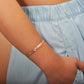 The photo shows the arm of a model wearing a rose gold vermeil flowering plumeria cuff bangle. 