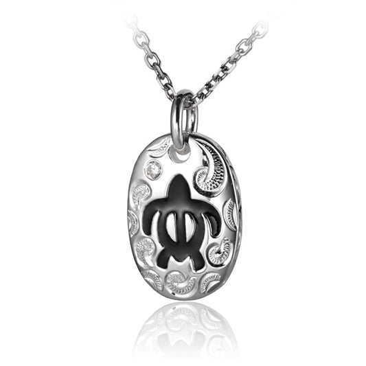 The photo shows a sterling silver black sea turtle petroglyph pendant with a scroll engraving with cubic zirconia.