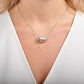The photo shows a model wearing a silver barrel Hawaiian scroll design pendant. 