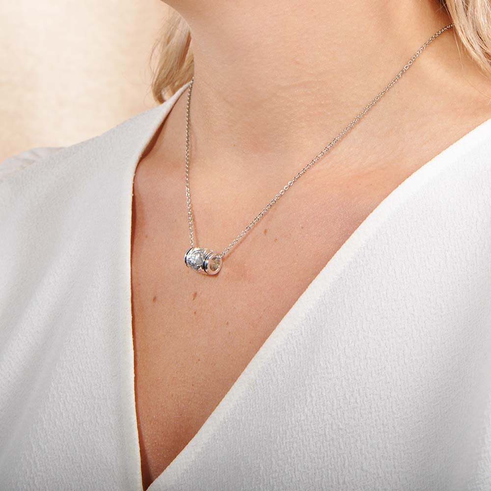 The photo is a model wearing a sterling silver scroll barrel pendant. 