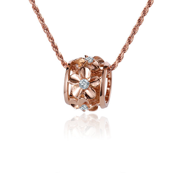 The photo shows a 14K rose gold plumeria barrel pendant featuring an original clear cubic zirconia in the center. 
