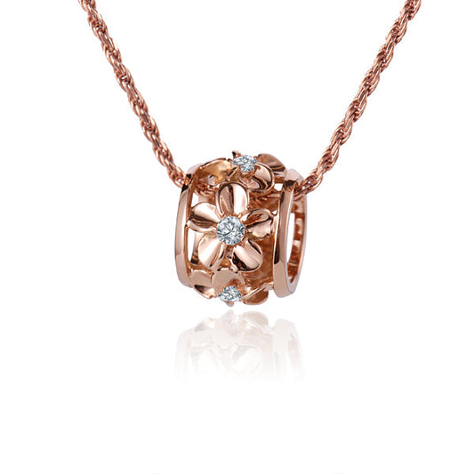 The photo shows a 14K rose gold plumeria barrel pendant featuring an original clear cubic zirconia in the center. 