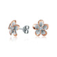 The picture shows a pair of rose gold vermeil sterling silver rhodium plated plumeria flower stud earrings with cubic zirconia gemstones in the center.  
