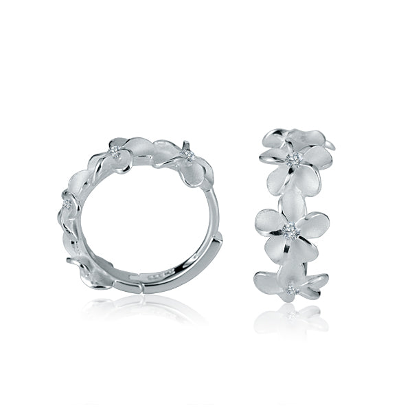 The picture shows a pair of matte finish sterling silver plumeria hoop earrings with white cubic zirconia. 