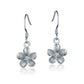 The photo shows a pair of sterling silver plumeria hook earrings with cubic zirconia. 