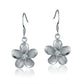 The photo show white sterling silver rhodium plated plumeria hook earrings with cubic zirconia stones. 
