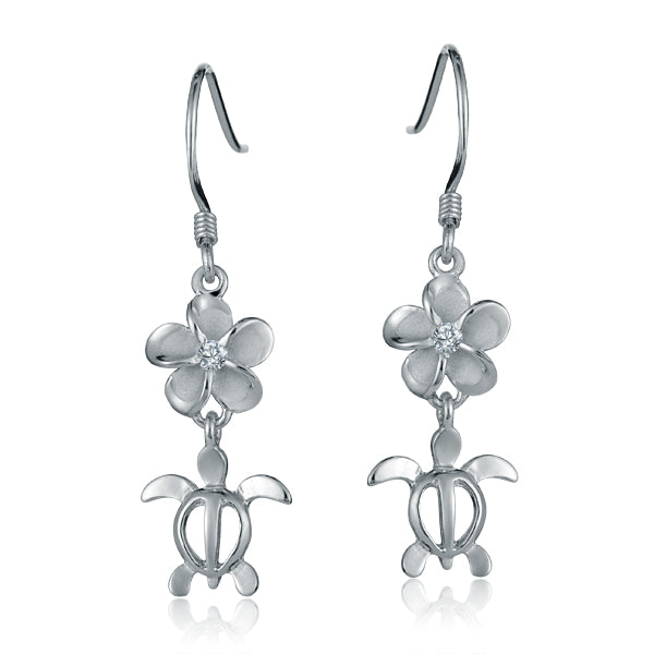The photo shows a pair of white gold vermeil plumeria and sea turtle hook earrings with cubic zirconia.
