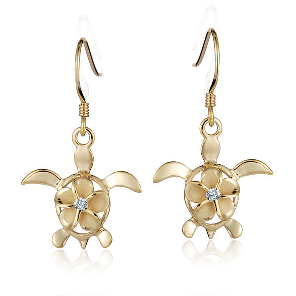 The photo shows a pair of yellow gold vermeil sea turtle hook earrings featuring a plumeria flower with a cubic zirconia gem. 