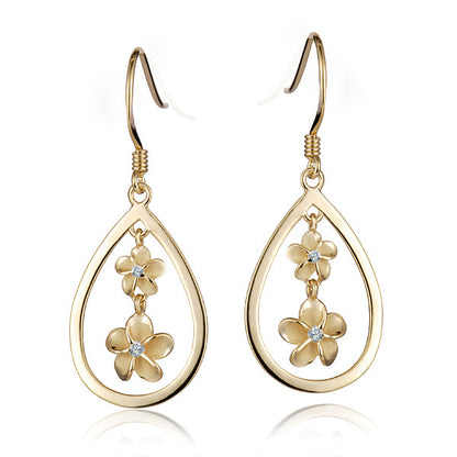 The photo shows a pair of yellow gold vermeil plumeria hook earrings featuring a teardrop design with cubic zirconia. 