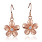 The picture shows a pair of rose gold vermeil plumeria hook earrings with cubic zirconia gems.
