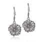 The photo shows a pair of white gold vermeil hibiscus hook earrings. 
