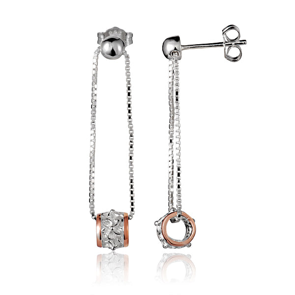 The photo shows a sterling silver and rose gold vermeil pair of dangling earrings featuring our plumeria and barrel design.
